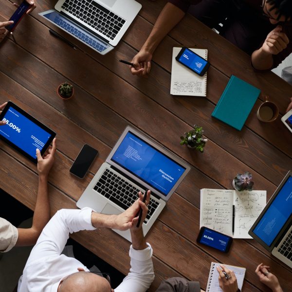 Imagen vista desde arriba de una mesa, se ve gente trabajando con computadoras.
